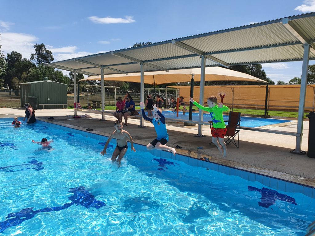 Children jumping into a swimming pool on a sunny day in Goolgowi. 